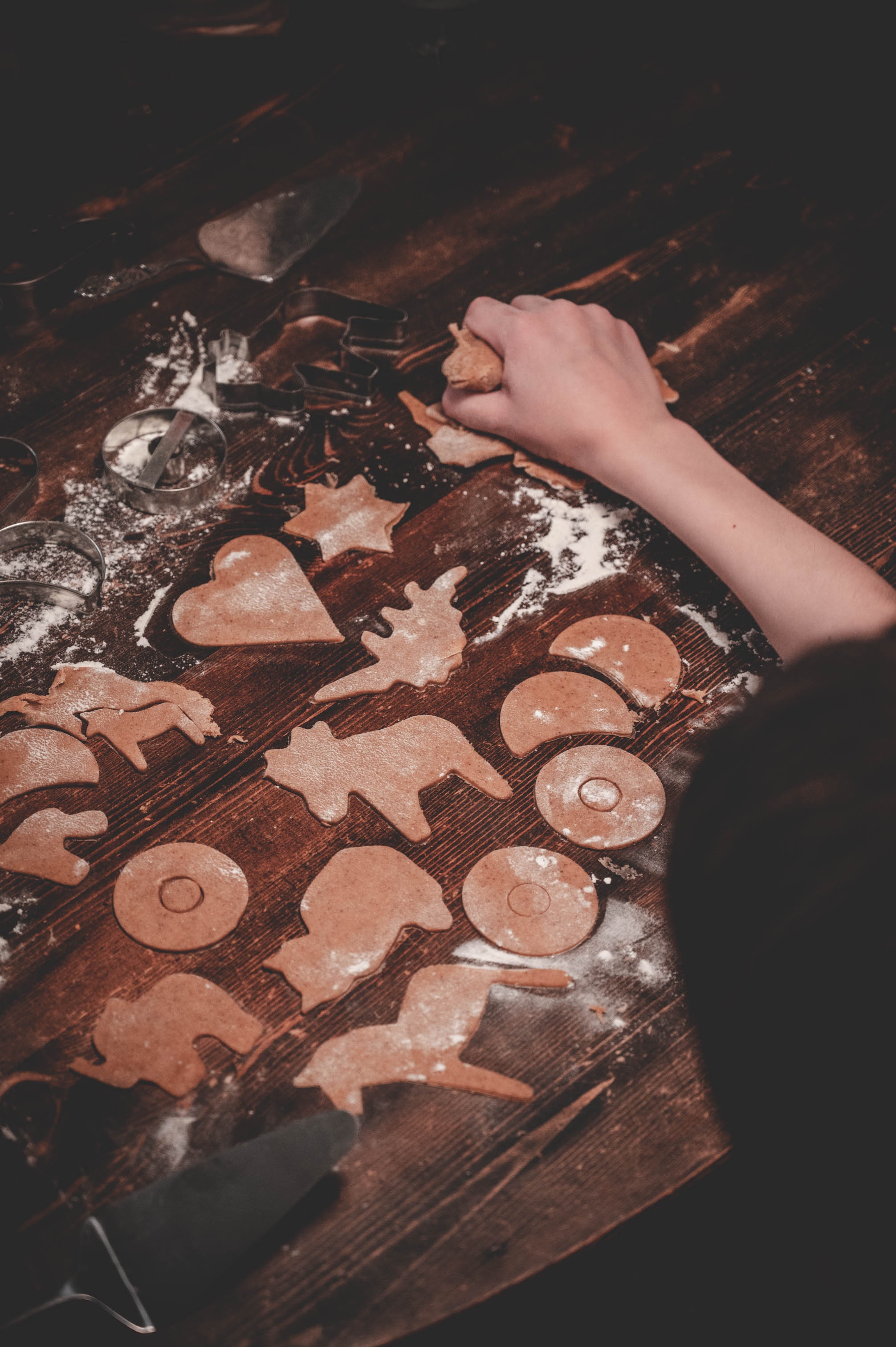 Hands cutting cookie shapes from dough on a floured surface